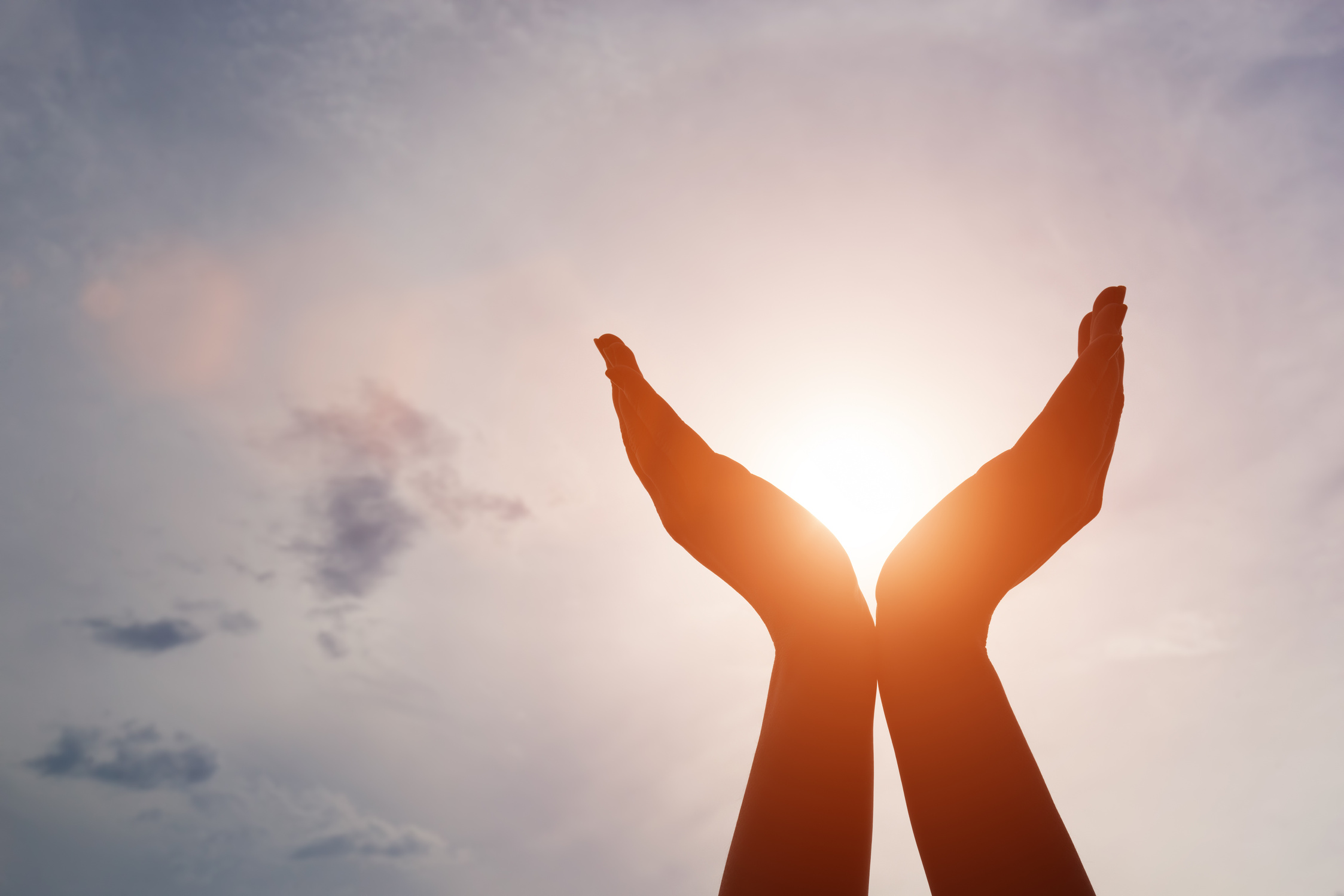 Raised Hands Catching Sun on Sunset Sky. Concept of Spirituality, Wellbeing, Positive Energy